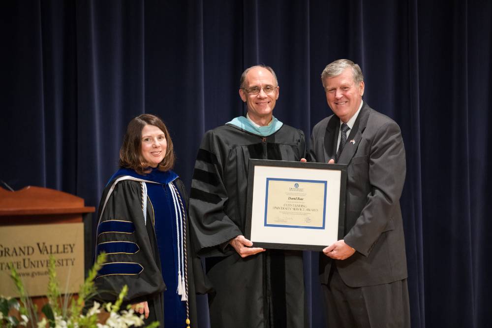 An awardee holds up his certificate with President Emeritus Haas and Provost Cimitile.